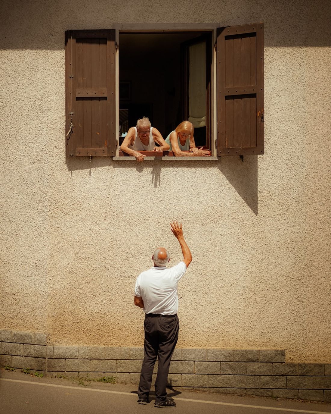Strassenfotografie – Mann winkt zu einem Fenster hinauf